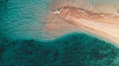aerial-shot-ocean-waves-hitting-small-sandy-island