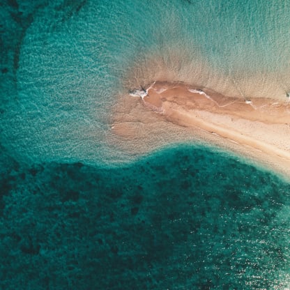 aerial-shot-ocean-waves-hitting-small-sandy-island