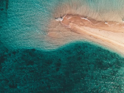 aerial-shot-ocean-waves-hitting-small-sandy-island
